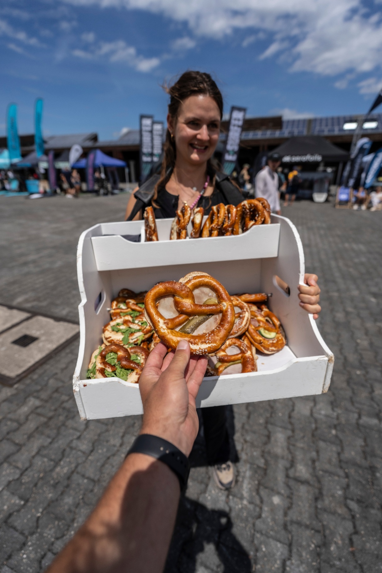 Frau mit Brezn-Bauchladen auf dem Eventgelände, Community-Moment