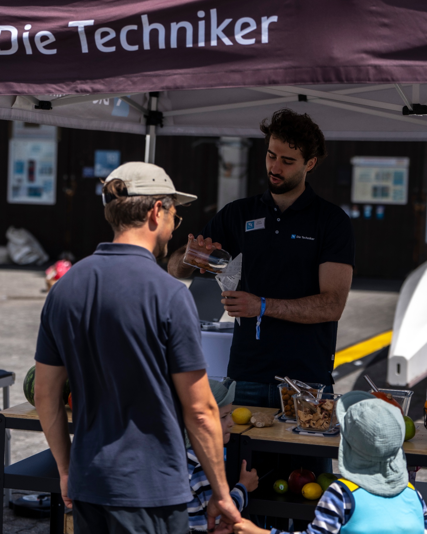 Familie im Gespräch am Stand von Die Techniker, Community-Atmosphäre