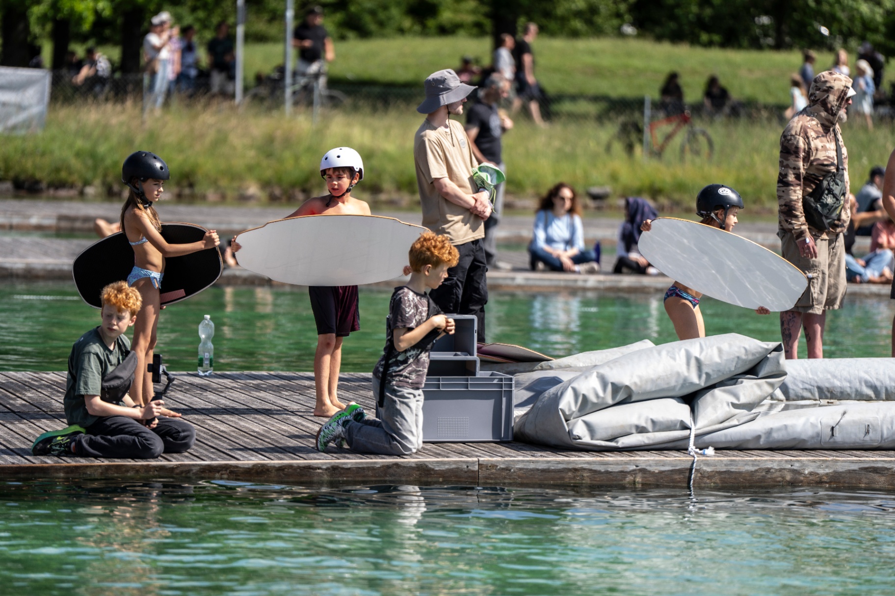 Kinder mit Skimboards auf dem Steg an der Regattaanlage