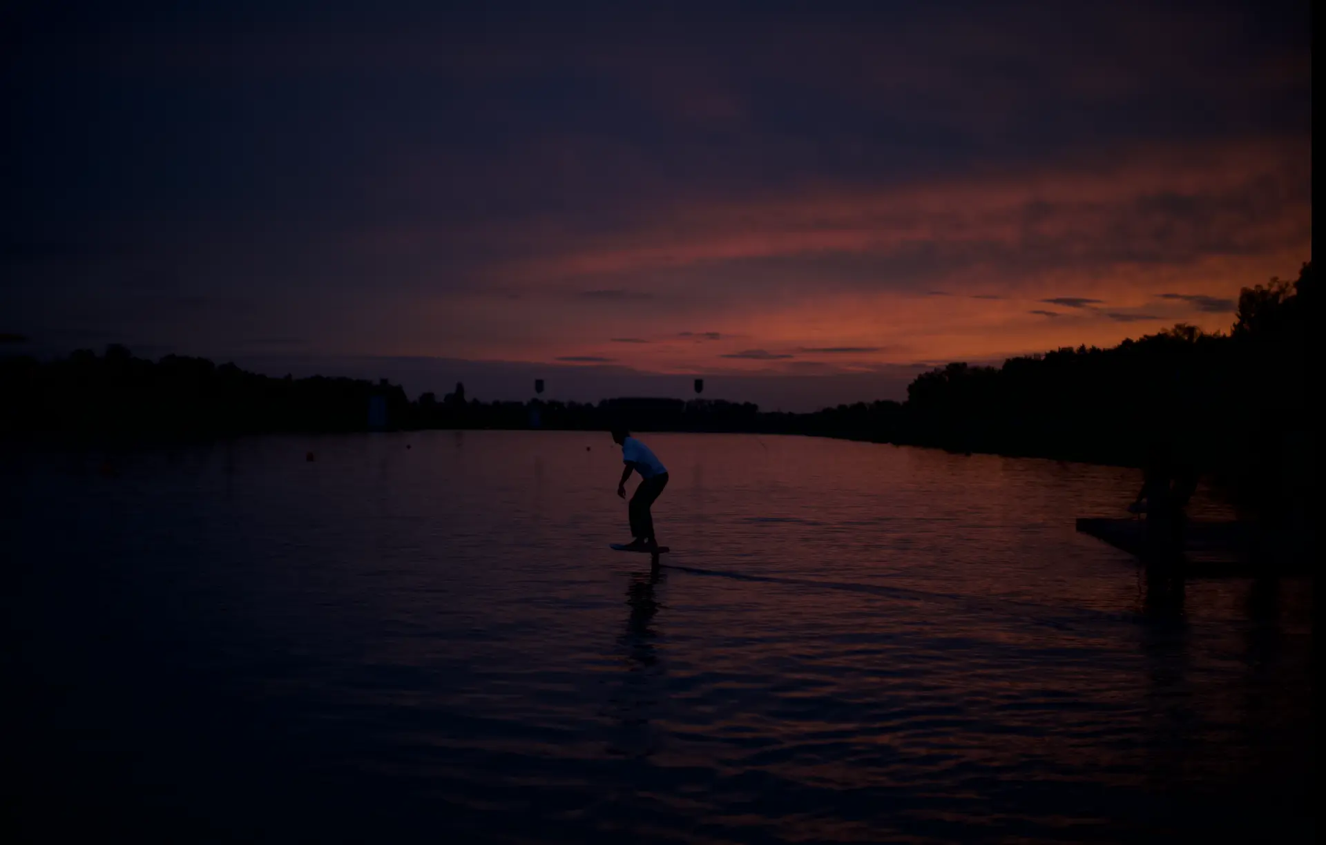 Pumpfoil-Rider als Silhouette gegen orangefarbenen Sonnenuntergang